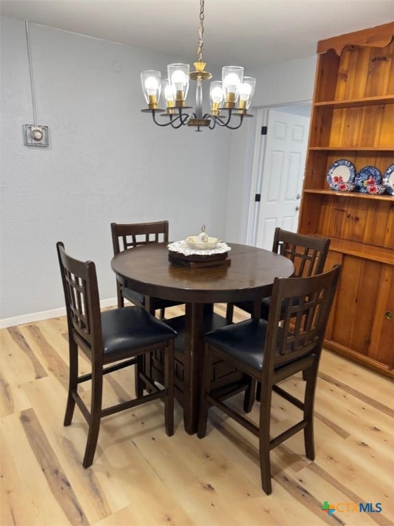 dining area featuring an inviting chandelier, baseboards, and light wood finished floors