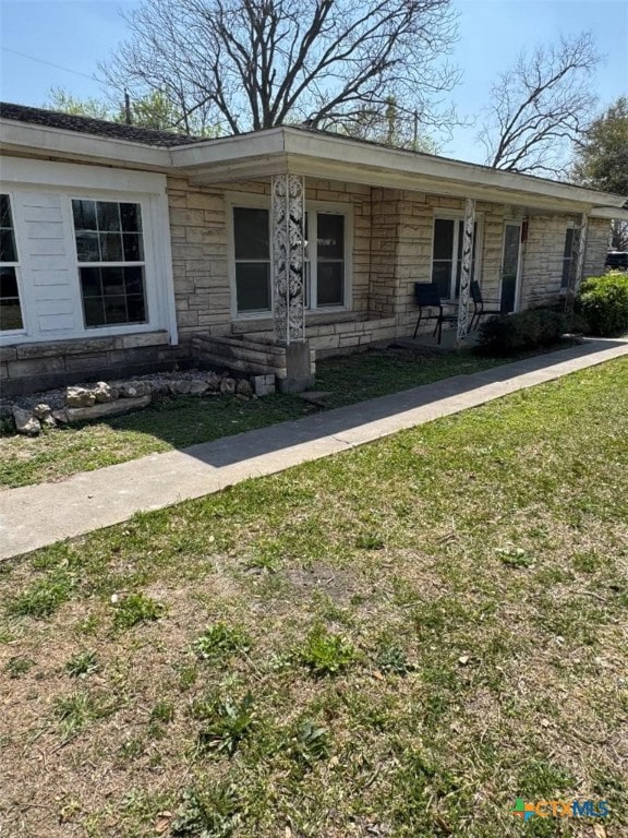 view of front of home with a front lawn and stone siding