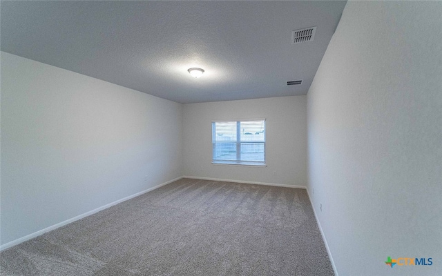 carpeted spare room with baseboards, visible vents, and a textured ceiling