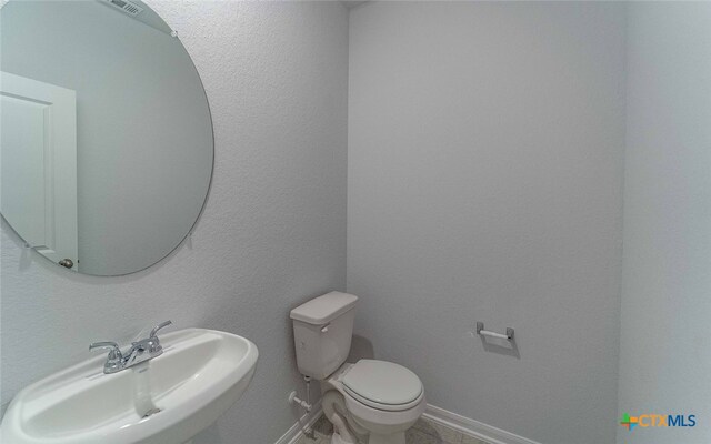 bathroom featuring toilet, visible vents, baseboards, and a sink