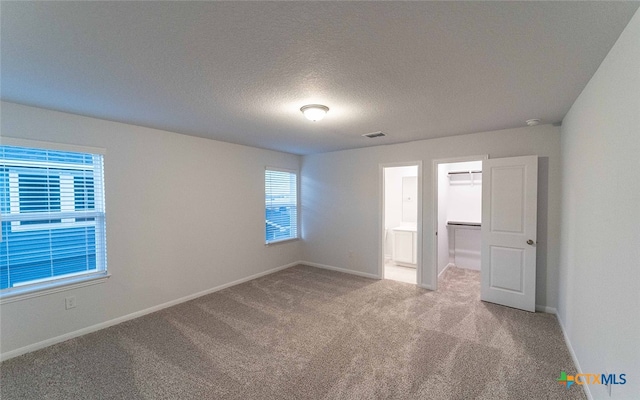 unfurnished room featuring a healthy amount of sunlight, light carpet, and a textured ceiling