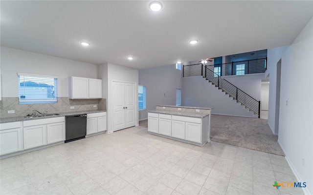 kitchen with tasteful backsplash, black dishwasher, light stone countertops, white cabinets, and light colored carpet