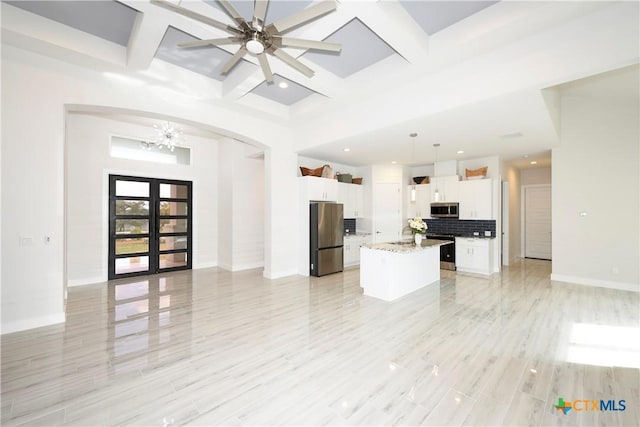 kitchen featuring a center island, hanging light fixtures, stainless steel appliances, tasteful backsplash, and white cabinets