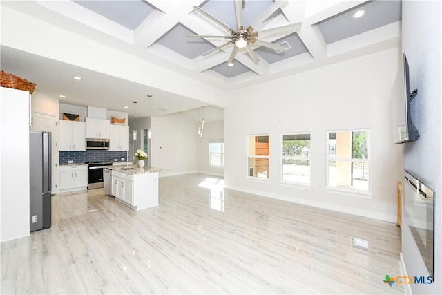 kitchen featuring light stone counters, stainless steel appliances, a center island with sink, white cabinets, and light hardwood / wood-style floors