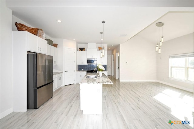 kitchen featuring white cabinetry, sink, stainless steel appliances, decorative light fixtures, and a center island with sink