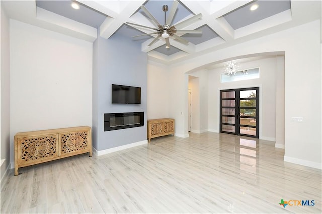 unfurnished living room with beam ceiling, light hardwood / wood-style floors, and coffered ceiling