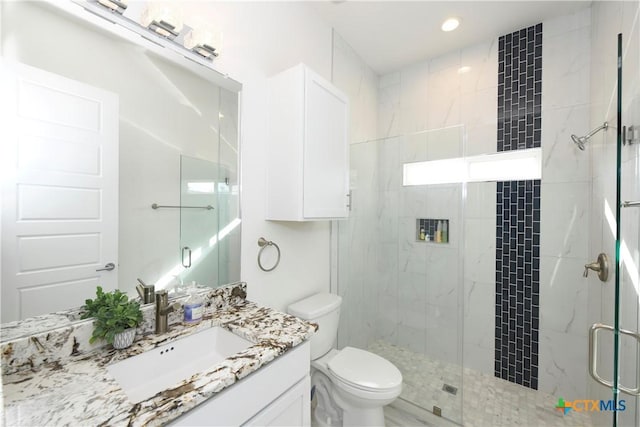 bathroom with a shower with door, vanity, and toilet