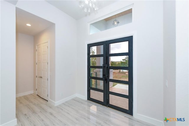 foyer featuring a chandelier, light hardwood / wood-style flooring, and french doors