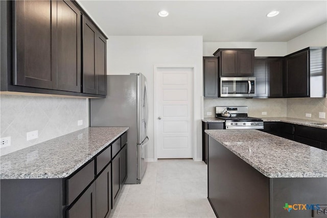 109 Cypress Hills Rd, San Marcos, TX 78666 - kitchen with stainless steel appliances, dark brown cabinets, tasteful backsplash, recessed lighting, and light stone countertops