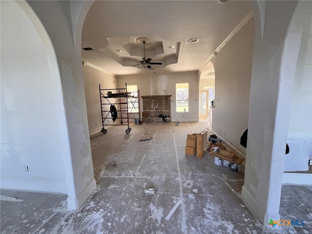 interior space featuring arched walkways, a raised ceiling, visible vents, ornamental molding, and baseboards