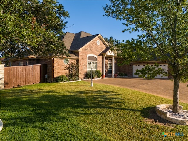 view of front of house with driveway, a shingled roof, fence, a front yard, and brick siding