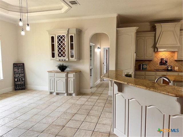 1004 Shady Hollow Ct, Nolanville, TX 76559 - kitchen featuring custom range hood, arched walkways, tasteful backsplash, light stone counters, and ornamental molding