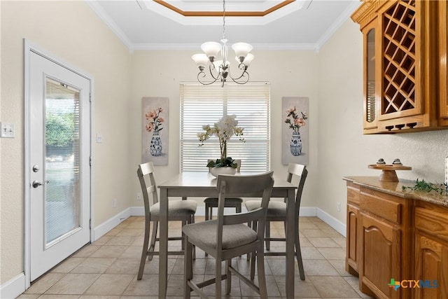 dining area with baseboards, ornamental molding, a raised ceiling, and a notable chandelier