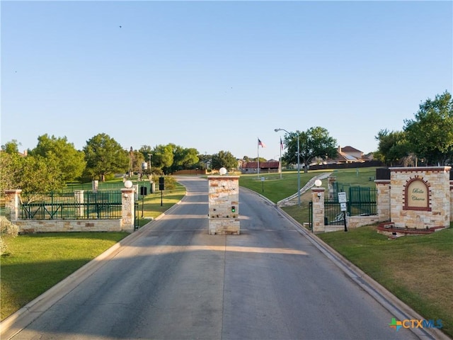 view of street with street lighting, curbs, and a gated entry