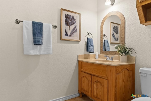 half bath featuring vanity, toilet, and baseboards