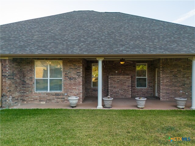 rear view of house featuring roof with shingles and brick siding