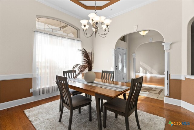 dining area with an inviting chandelier, arched walkways, and wood finished floors