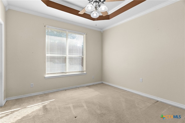 carpeted empty room with ornamental molding, a raised ceiling, ceiling fan, and baseboards