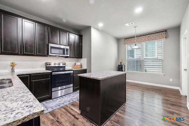 kitchen featuring pendant lighting, a textured ceiling, stainless steel appliances, and a kitchen island