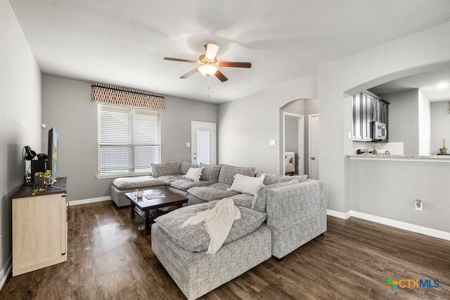 living room featuring a textured ceiling, ceiling fan, and dark wood-type flooring