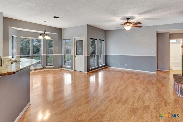 106 Hamlet Ct, Victoria, TX 77901 - unfurnished living room featuring a textured ceiling, ceiling fan, light wood-style floors, and a chandelier
