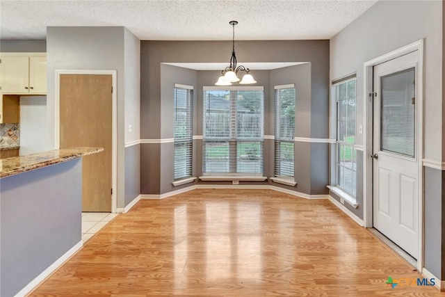 106 Hamlet Ct, Victoria, TX 77901 - unfurnished dining area featuring light wood-style flooring, a textured ceiling, and a chandelier