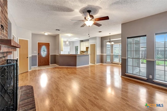 106 Hamlet Ct, Victoria, TX 77901 - unfurnished living room with a fireplace, a ceiling fan, light wood-type flooring, a textured ceiling, and a chandelier