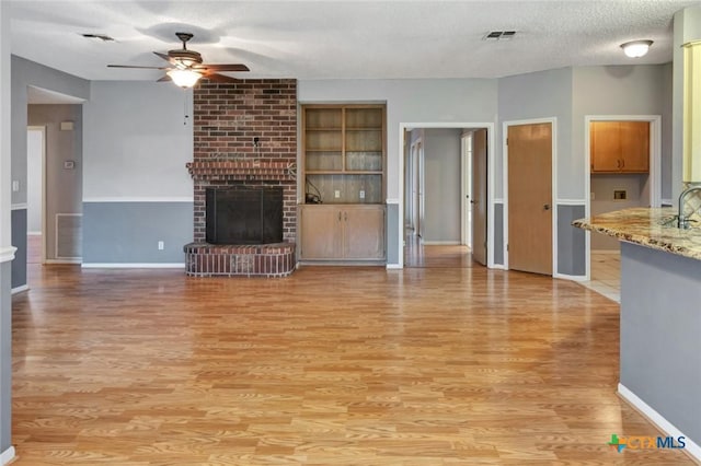 106 Hamlet Ct, Victoria, TX 77901 - unfurnished living room featuring ceiling fan, light wood-style floors, a fireplace, and a textured ceiling