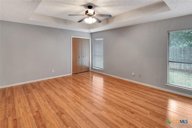 106 Hamlet Ct, Victoria, TX 77901 - empty room with a raised ceiling, a textured ceiling, light wood finished floors, and ceiling fan