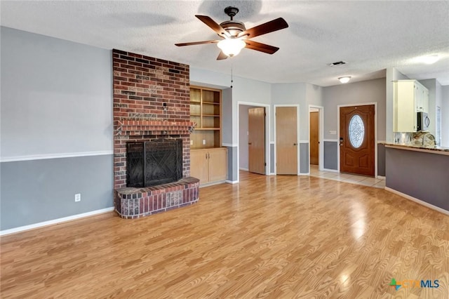 106 Hamlet Ct, Victoria, TX 77901 - unfurnished living room with a ceiling fan, a textured ceiling, light wood-style flooring, and a fireplace