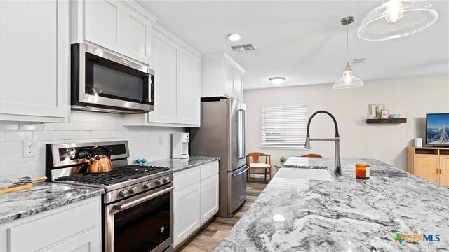 1406 Shannon Cir, New Braunfels, TX 78130 - kitchen featuring stainless steel appliances, white cabinets, decorative backsplash, wood finished floors, and light stone counters