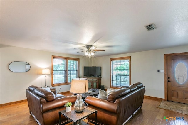 living area featuring baseboards, visible vents, and wood finished floors