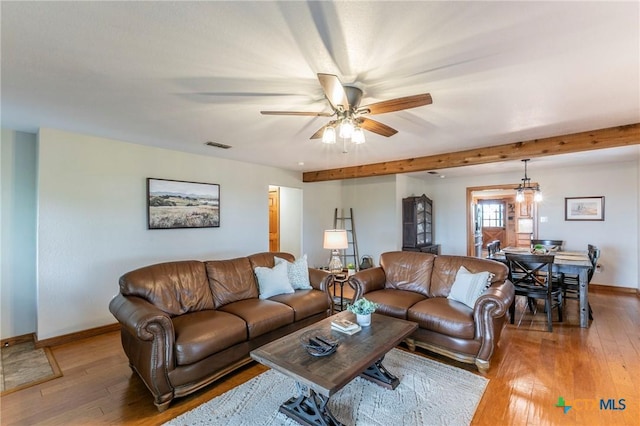 living room featuring ceiling fan, visible vents, beam ceiling, baseboards, and light wood finished floors