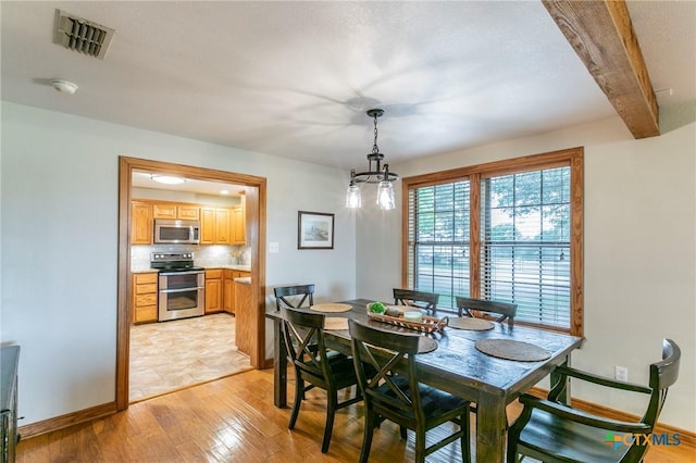 dining room with visible vents, baseboards, beamed ceiling, light wood finished floors, and a chandelier