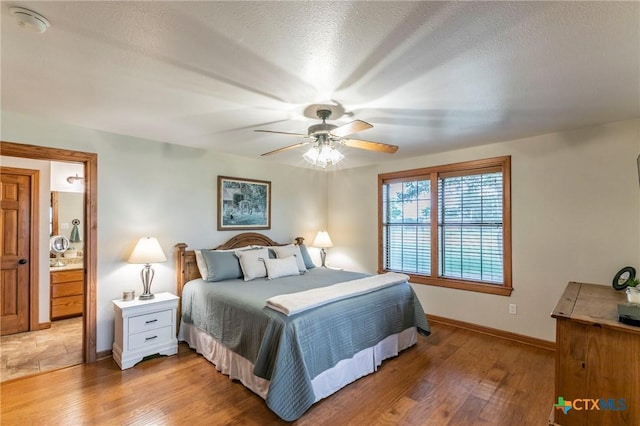 bedroom featuring light wood-style floors, baseboards, ceiling fan, and connected bathroom