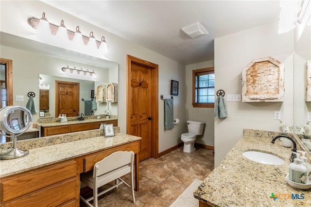 bathroom featuring visible vents, two vanities, a sink, baseboards, and toilet
