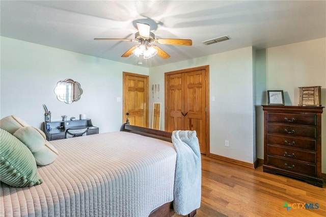 bedroom with visible vents, a closet, wood finished floors, baseboards, and a ceiling fan