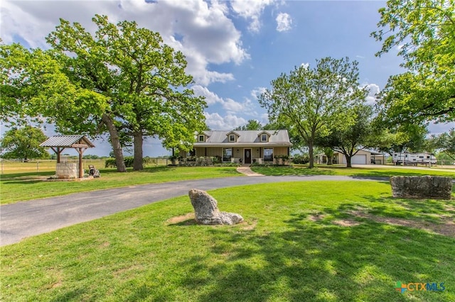 view of front of house featuring a detached garage, a gazebo, a front yard, and aphalt driveway