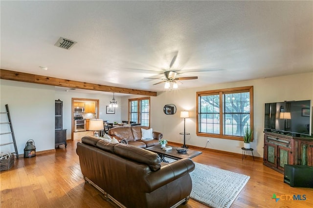 living area with visible vents, wood finished floors, beam ceiling, baseboards, and ceiling fan