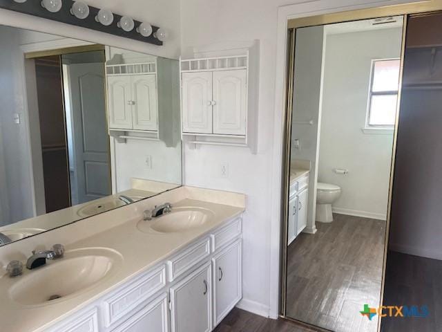 bathroom with toilet, vanity, and hardwood / wood-style floors