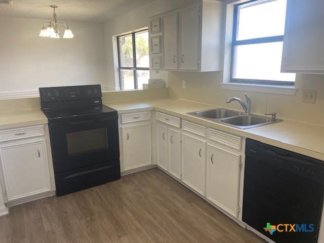 kitchen with sink, white cabinets, hanging light fixtures, black appliances, and a notable chandelier