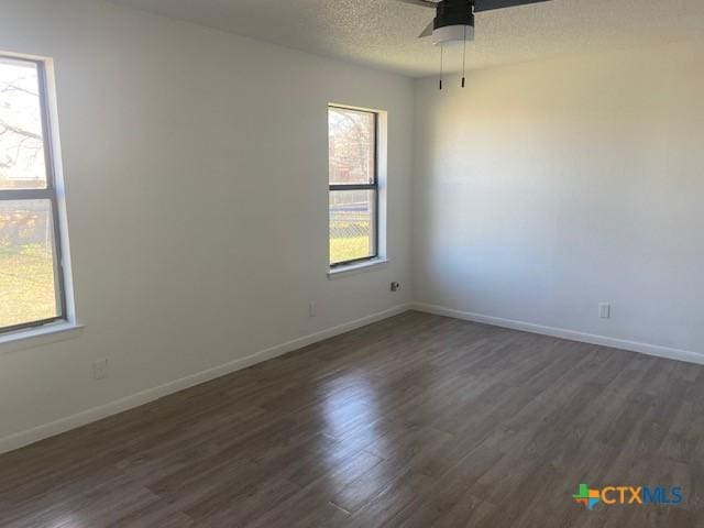 spare room with dark hardwood / wood-style flooring, ceiling fan, and plenty of natural light