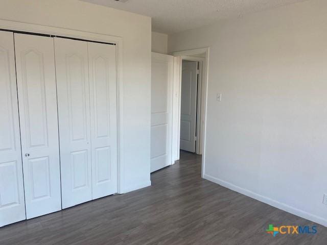 unfurnished bedroom featuring a closet and dark hardwood / wood-style floors