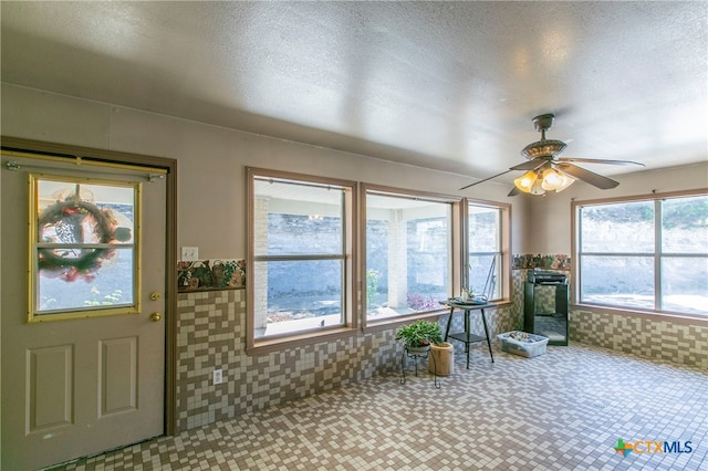 unfurnished sunroom featuring ceiling fan