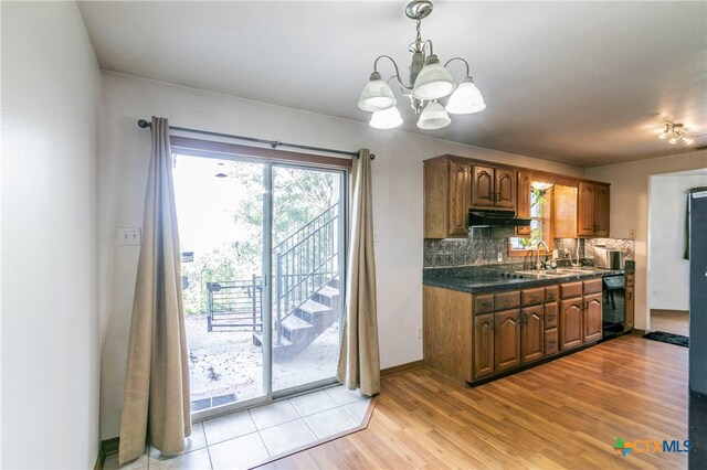 kitchen with backsplash, a notable chandelier, hanging light fixtures, sink, and light hardwood / wood-style floors