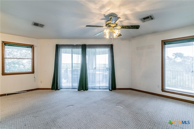 carpeted spare room featuring plenty of natural light and ceiling fan