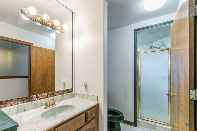 bathroom featuring toilet, tile patterned floors, vanity, and a shower with door