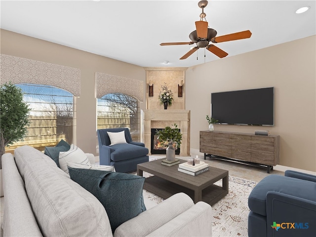 living room featuring a large fireplace and ceiling fan