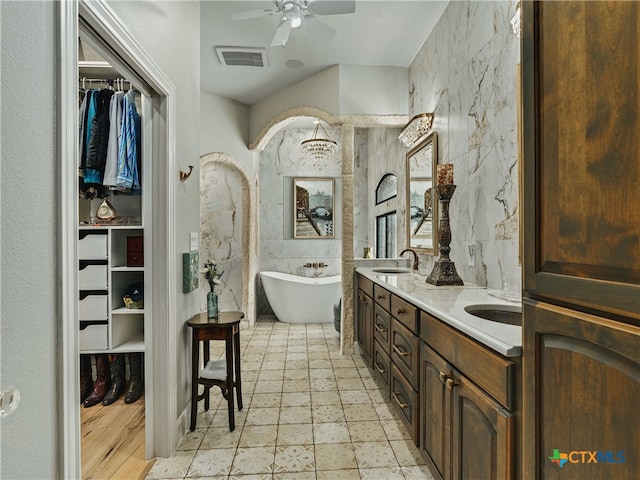 bathroom with vanity, a tub to relax in, tile walls, and ceiling fan