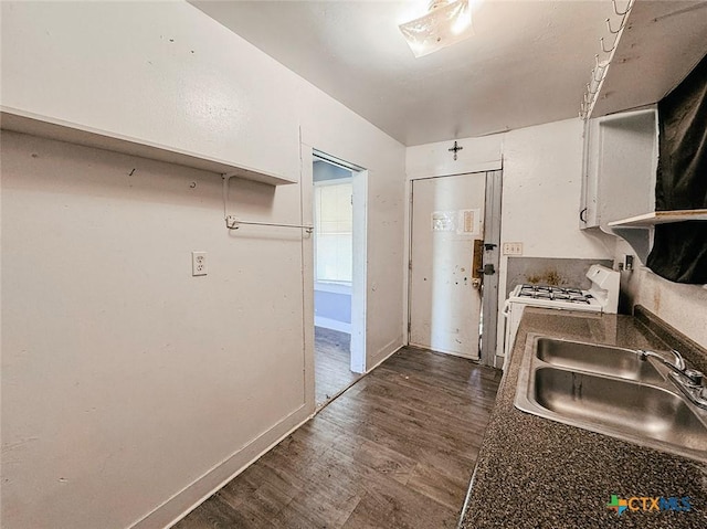 kitchen featuring stove, sink, dark wood-type flooring, and white cabinets